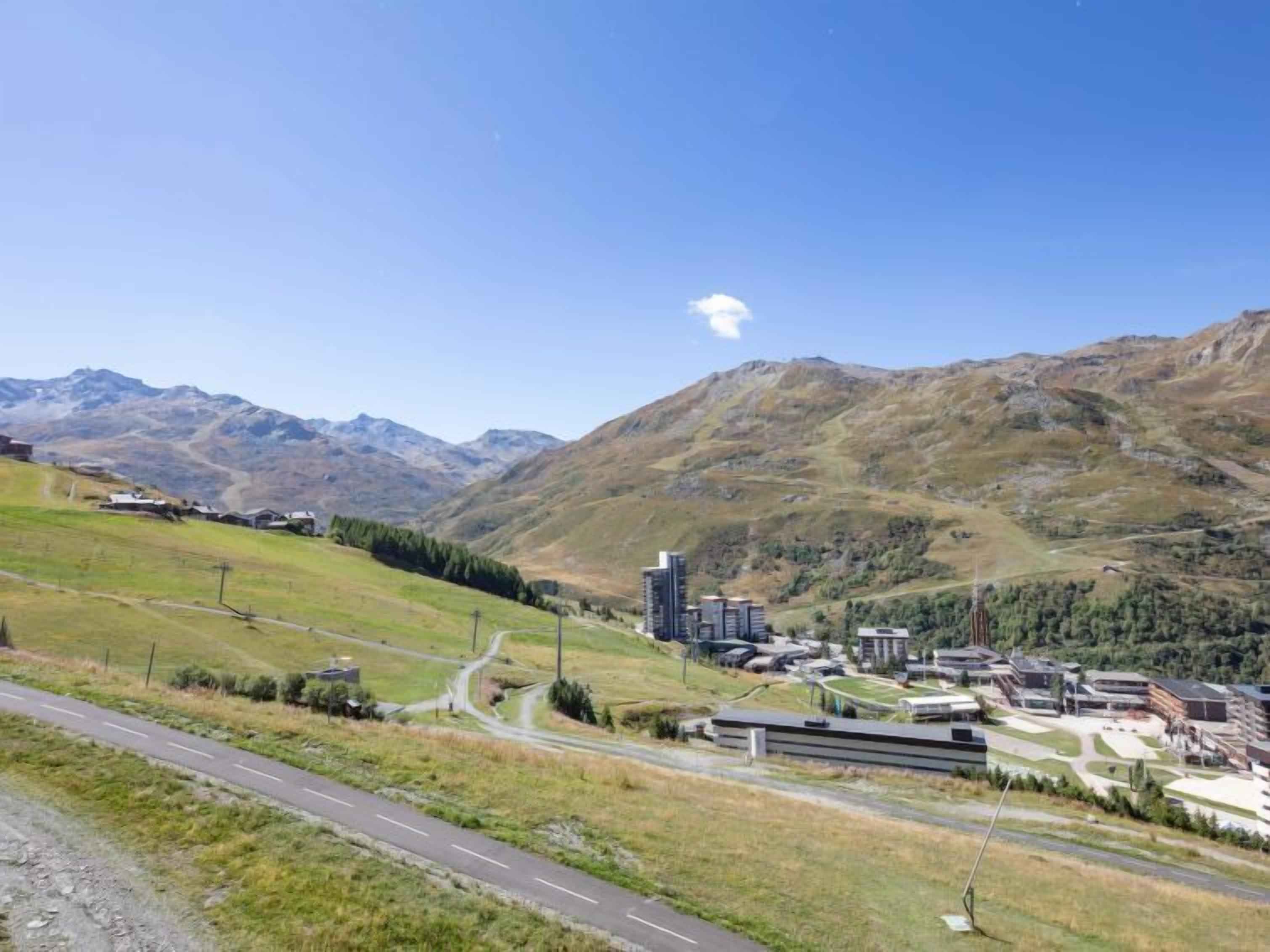 Un paysage montagneux avec une route menant à un ensemble de bâtiments modernes.