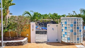 Un ingresso recintato con un muro in pietra, una piccola area piscina e una struttura in vetro decorativa.