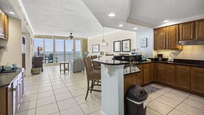 A spacious kitchen with a large island, wooden cabinets, and a view to the outside. - The Colonnades 1002 by Liquid Life (Gulf Shores)