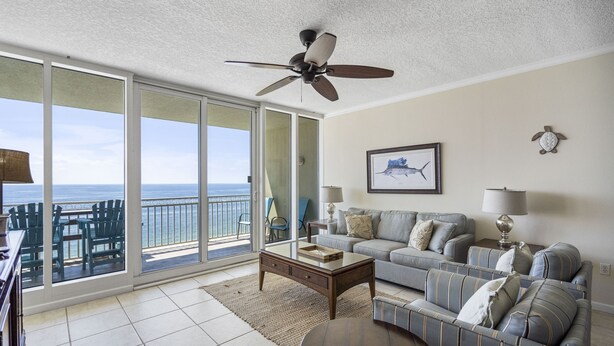 A living room with a balcony, a ceiling fan, a sofa set, a coffee table, and a framed picture on the wall. - The Colonnades 1002 by Liquid Life (Gulf Shores)