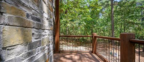 A wooden deck with a stone wall, surrounded by a forest.