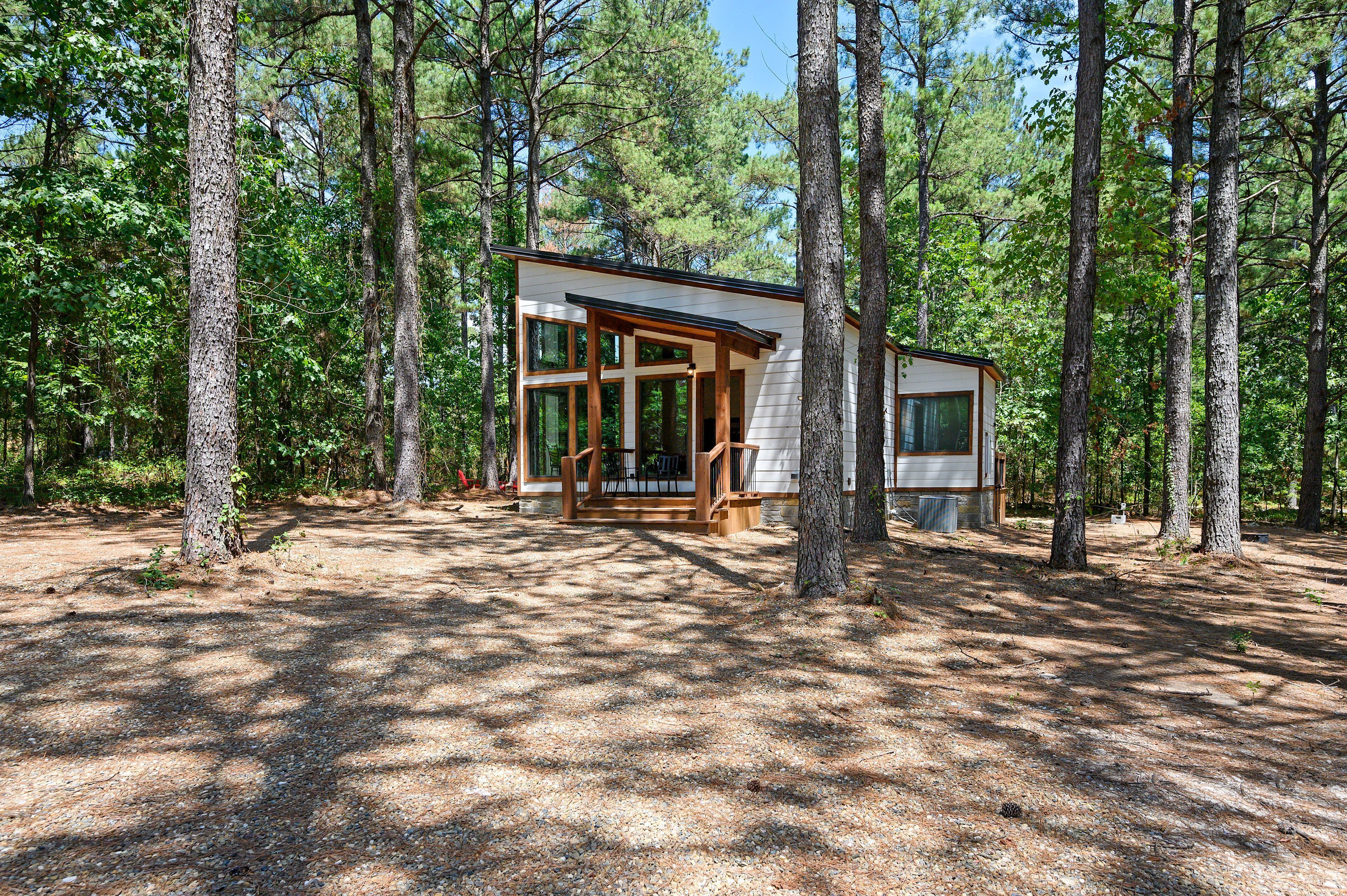 A modern cabin in a forest with large windows and a deck.