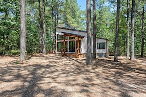 Uma cabana moderna em uma floresta, com janelas amplas e um deck.