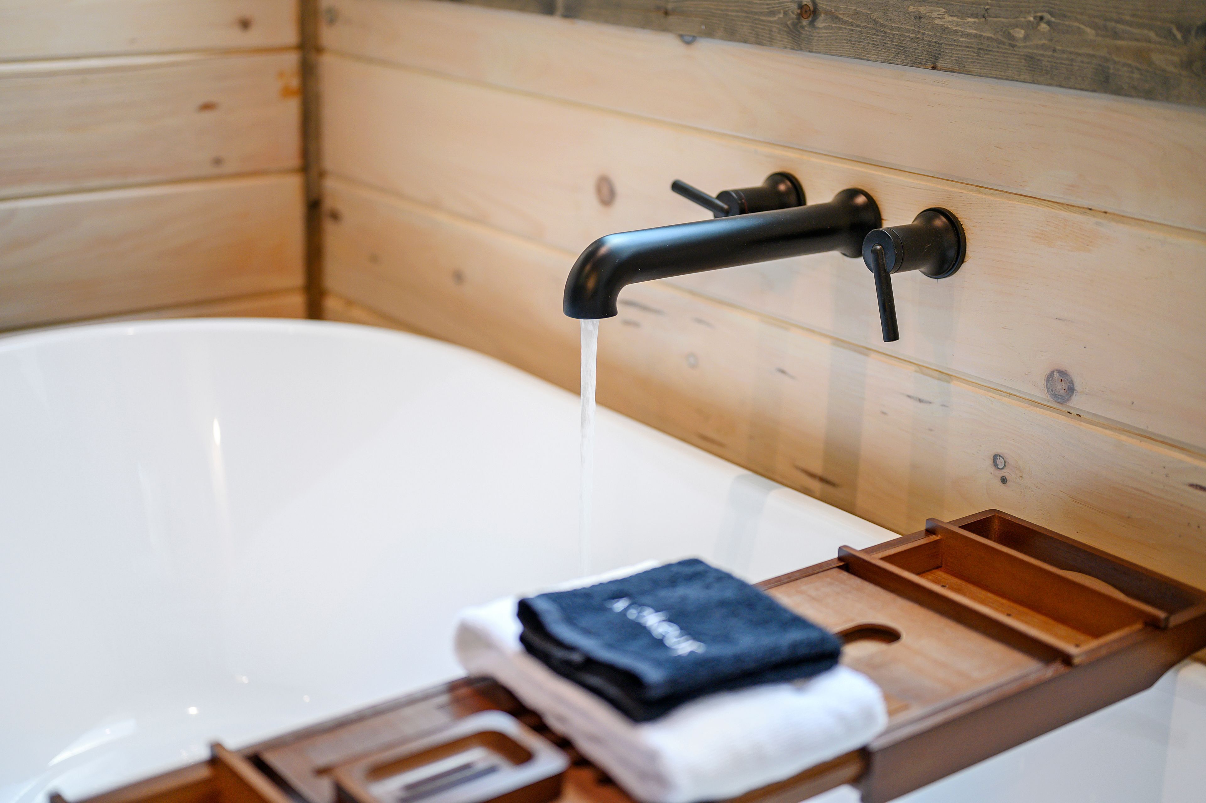 Interior de una cabaña de madera con una bañera, una toalla y una bandeja de madera.
