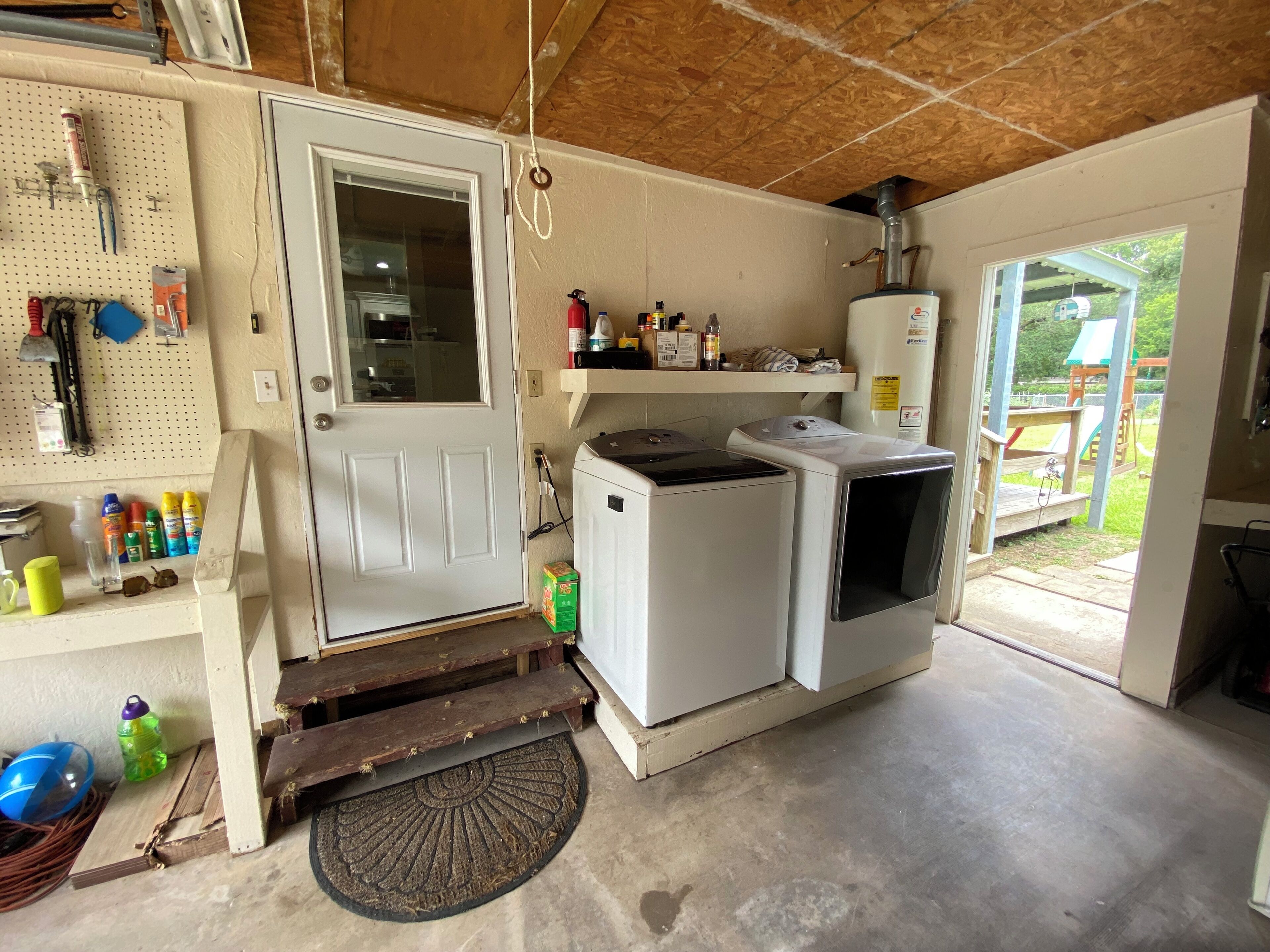 A laundry room with a washing machine, dryer, and a pegboard with cleaning supplies.