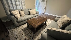 A living room with a grey sofa, a wooden coffee table, and patterned rugs. - The Nest - 2 beds, 1 bath - Quiet & Comfortable  (Groves)