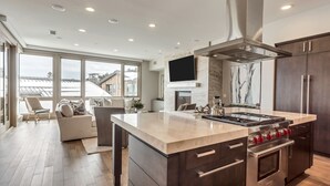A modern kitchen with a large island, stainless steel appliances, and a flat-screen TV mounted above the island. - Premium Five Bedroom Suite 5 Apartment Hotel by Redawning (Park City)