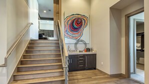 A staircase with wooden steps and metal railings leading to a kitchen area with dark cabinets and a countertop. - Four Bedroom Penthouse 4 Apartment Hotel by RedAwning (Park City)