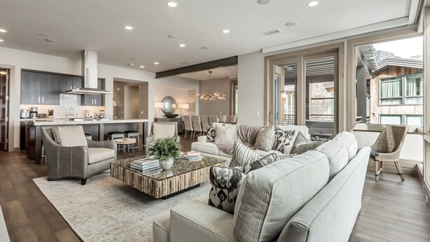 A spacious living room with a large sofa, a coffee table, and a dining area with a kitchen in the background.