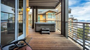 A wooden deck with a hot tub, a small table, and a chair.