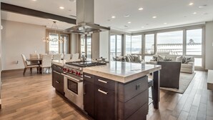 A modern kitchen with a central island, built-in oven, and a dining area with a table and chairs.