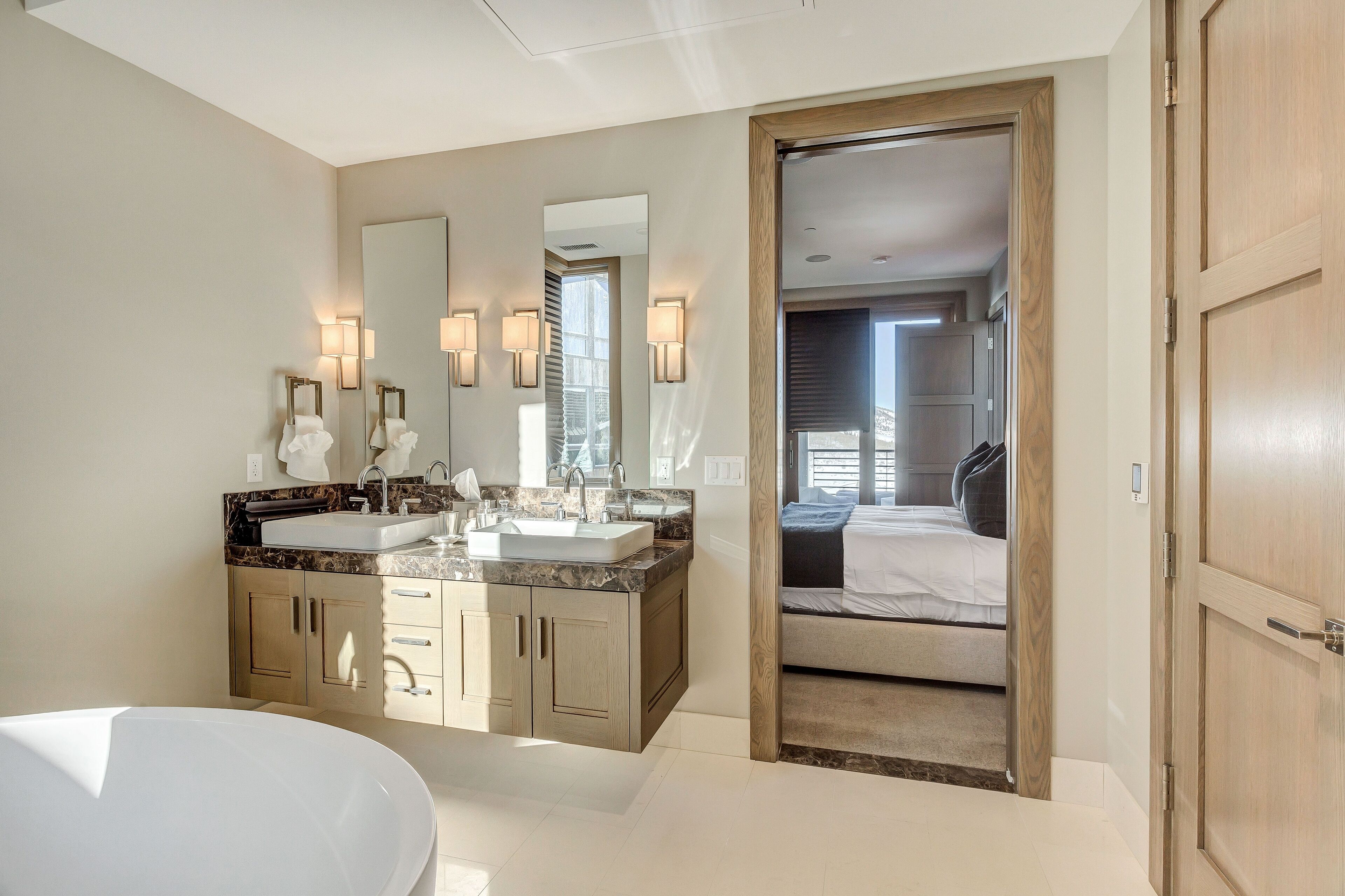 A modern bathroom with two sinks, a large mirror, and a walk-in shower.