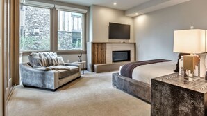 A modern bedroom with a sofa, a bed, a TV, and a fireplace. - Premium Junior Three Bedroom 3 Apartment Hotel by Redawning (Park City)