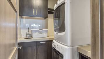 A compact kitchen with dark wood cabinets, a white washing machine, and a stainless steel sink.