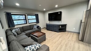 Een moderne woonkamer met een modulaire bank, een salontafel, een flatscreen televisie en een inbouwmeubel.
