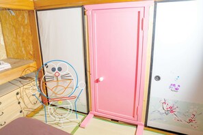 A room with a pink door, a white wall with a floral painting, and a chair with a colorful design. - Pet friendly private lodge OMOTENASHI LODGE　YOUYOU (空知郡上富良野町)