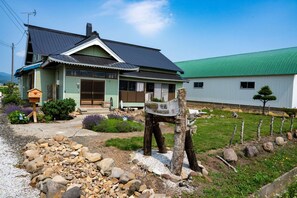 A traditional Japanese house with a green roof, a wooden mailbox, and a gravel pathway leading to the entrance. - Pet friendly private lodge OMOTENASHI LODGE　YOUYOU (空知郡上富良野町)