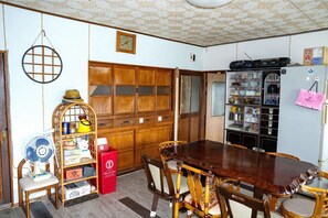 A dining area with a wooden table and chairs, a fan, a red cabinet, and a refrigerator with a pink shopping bag on it. - Pet friendly private lodge OMOTENASHI LODGE　YOUYOU (空知郡上富良野町)