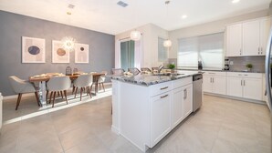 Una cocina moderna con armarios blancos, encimera de granito e iluminación colgante.