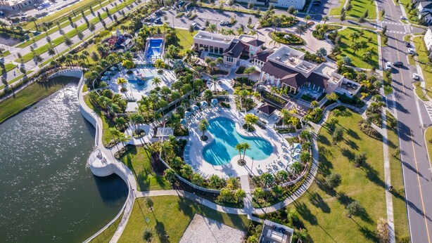 Vista aérea de un resort con piscina central, áreas ajardinadas y edificios residenciales.