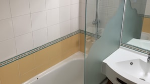 A bathroom with a bathtub, a glass shower enclosure, and a sink with a mirror. - Rental Apartment 2 room 26 M2 - Alps - Avoriaz - Douchka - Falaise (Morzine)