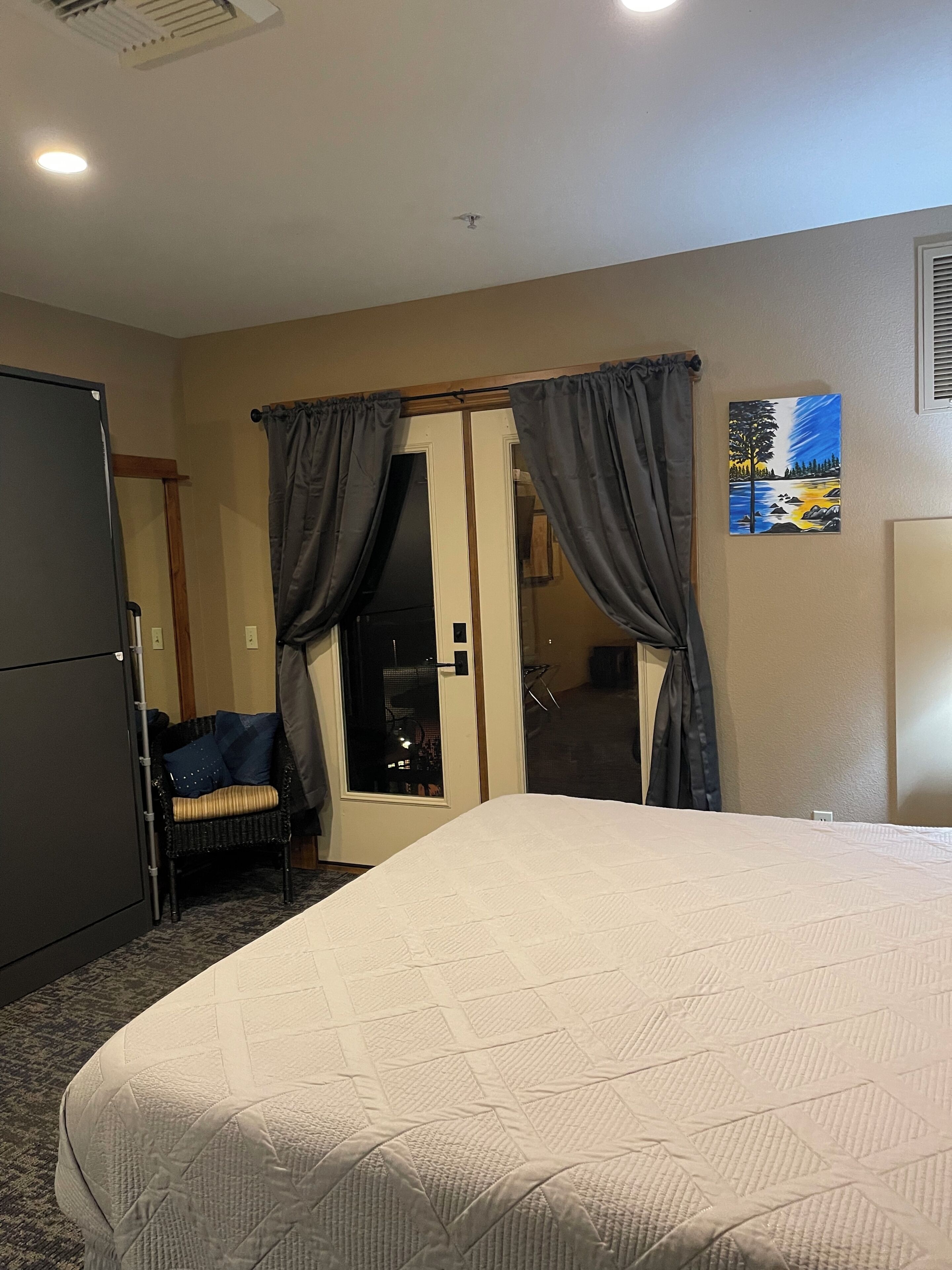 Une chambre d’hôtel avec un lit, une chaise, une porte et un tableau au mur.