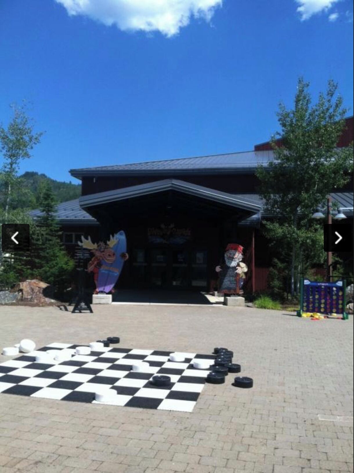 A building with a checkered floor game in front, a sign reading "Dine & Dine," and a mountain backdrop.