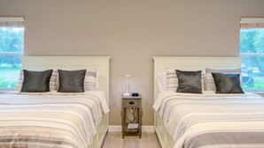 A double room with two beds, each with a headboard, a bedside table with a lamp, and a window providing a view of greenery outside. - HS#1- Modern Studio next to Premier Sports Complex (Bradenton)
