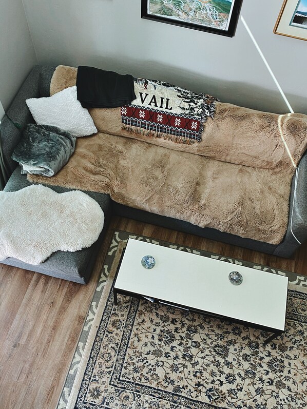 A cozy living room with a sofa, a small side table, and a patterned rug.