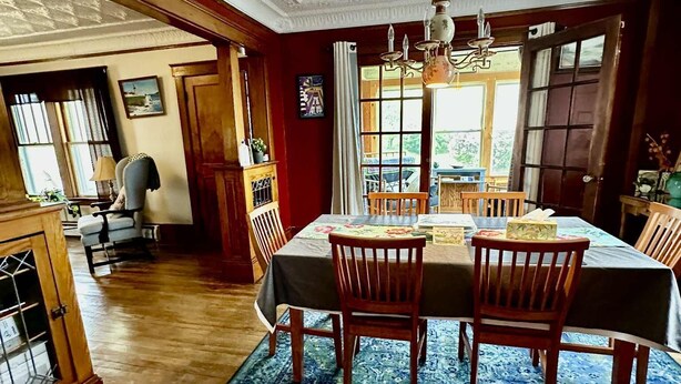 A dining room with a large table, wooden chairs, and a chandelier.