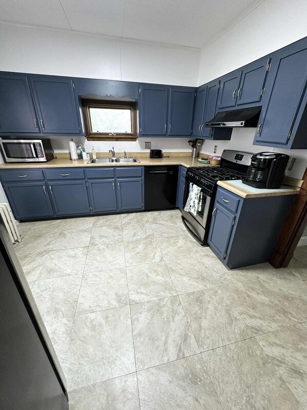A kitchen with blue cabinets, a microwave, a stove, and a sink.
