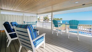 A covered outdoor area with wooden flooring, white railings, and seating with blue and white striped cushions.