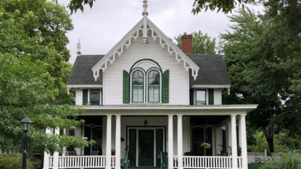 A two-story house with a porch, green shutters, and a chimney. - The Barron Historic Eau Claire Home (Eau Claire)