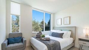 A bedroom with a bed, a chair, a bedside table, and a window. - Perch - Urban Reflections 13: WS 97! Spacious 3BR/2BA w Space Needle view (Seattle)