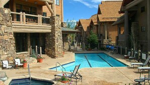 A pool area with stone walls, lounge chairs, and a wooden deck. - Gorgeous 4 bedroom ski-in/out condominium, immaculate interior!! (Bachelor Gulch)