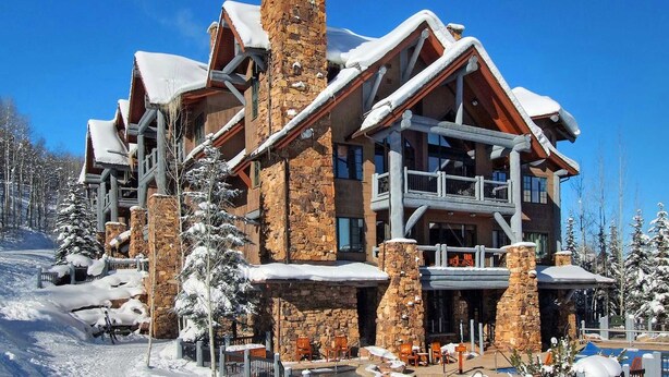 A multi-story lodge with stone and wood architecture, featuring balconies and large windows. - Gorgeous 4 bedroom ski-in/out condominium, immaculate interior!! (Bachelor Gulch)