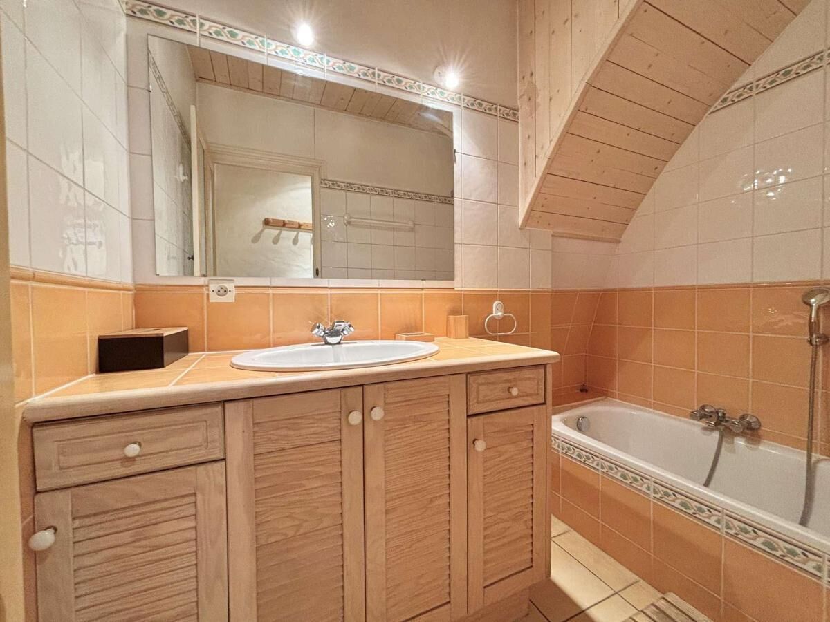 Une salle de bain avec un meuble-lavabo en bois, un évier et une baignoire.