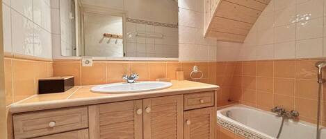 Une salle de bain avec un meuble-lavabo en bois, un évier et une baignoire.