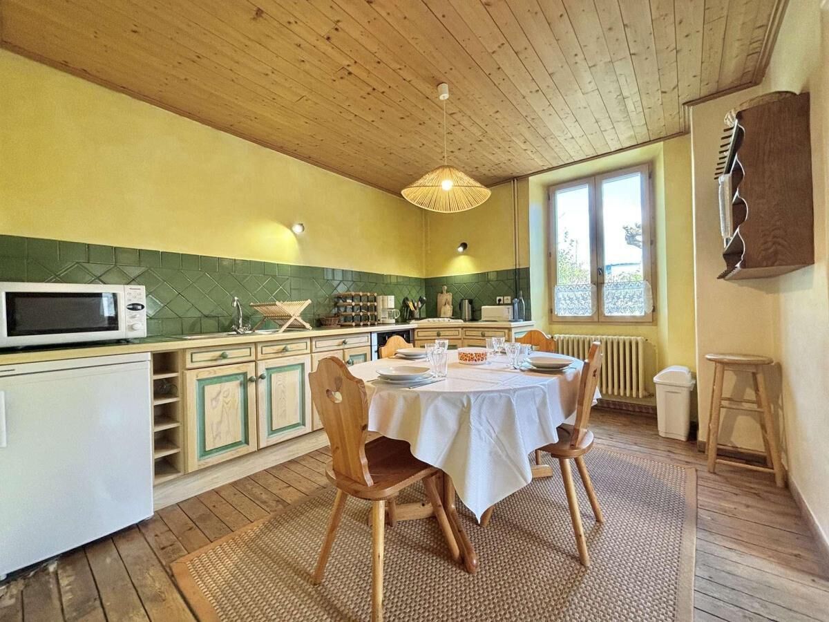 Una cocina con una mesa de comedor, sillas y una lámpara colgante.