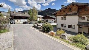 A rural road with traditional wooden houses, a clear sky, and mountains in the background. - Ground floor, tv, ski locker, 42m², Praz sur Arly (Praz-sur-Arly)
