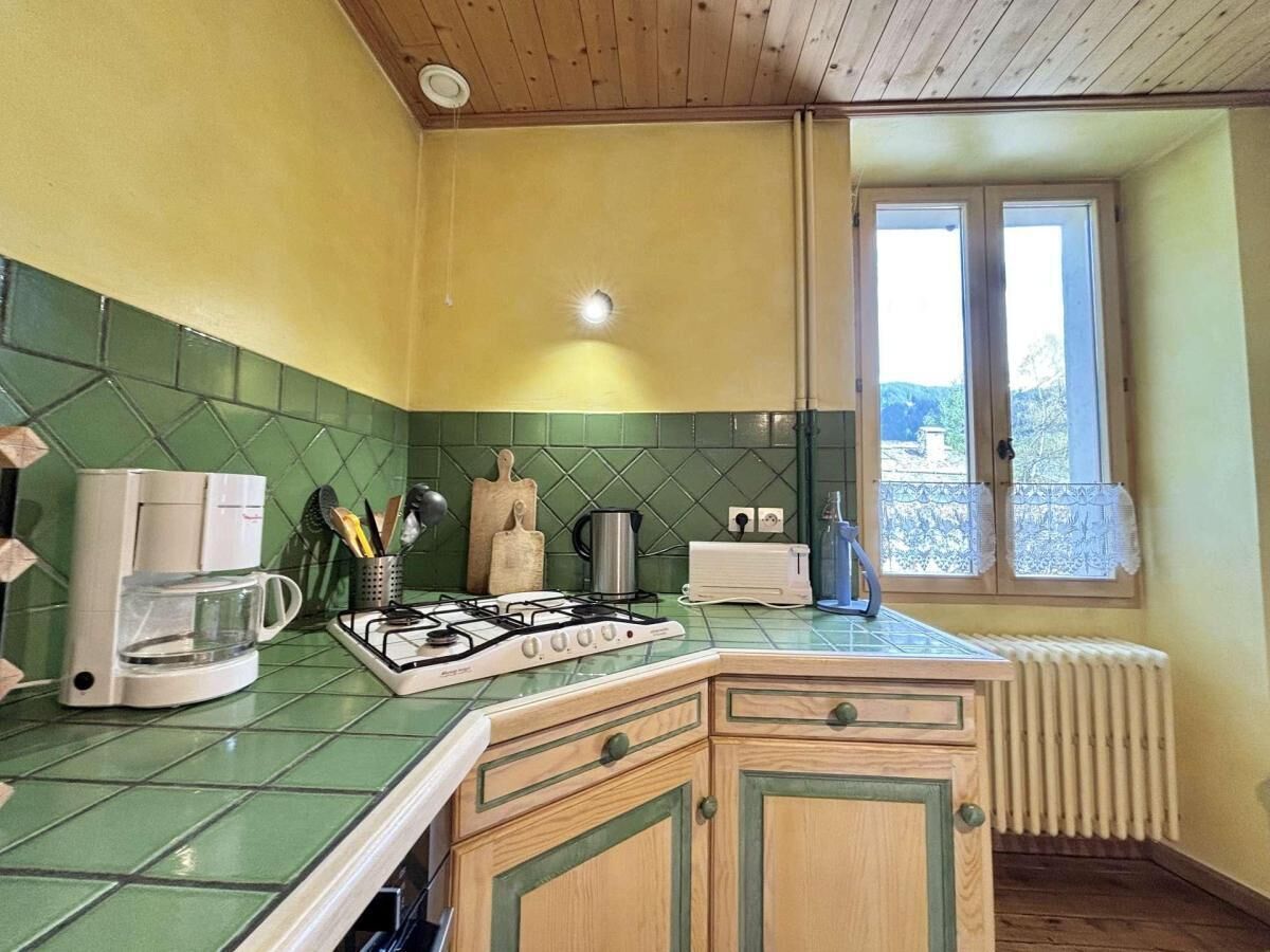A kitchen with a gas stove, a coffee maker, a toaster, and a window with a view of the outdoors.