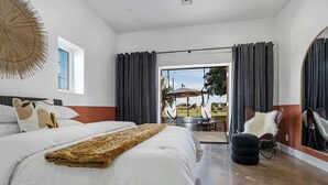 Una habitación de hotel moderna con una cama grande, vistas al exterior y un área de descanso con una silla y una mesa.