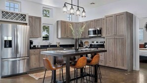 Una cocina moderna con una isla central, electrodomésticos de acero inoxidable y armarios de madera.