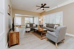 A living room with a sofa, armchair, coffee table, and TV stand. - THE PALMIERI luxe home with incredible pool area near DT SRQ (Sarasota)