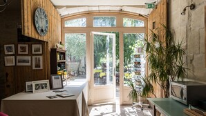 Una habitación acogedora con detalles de madera, un reloj en la pared, una mesa con varios objetos y una puerta que da al exterior.