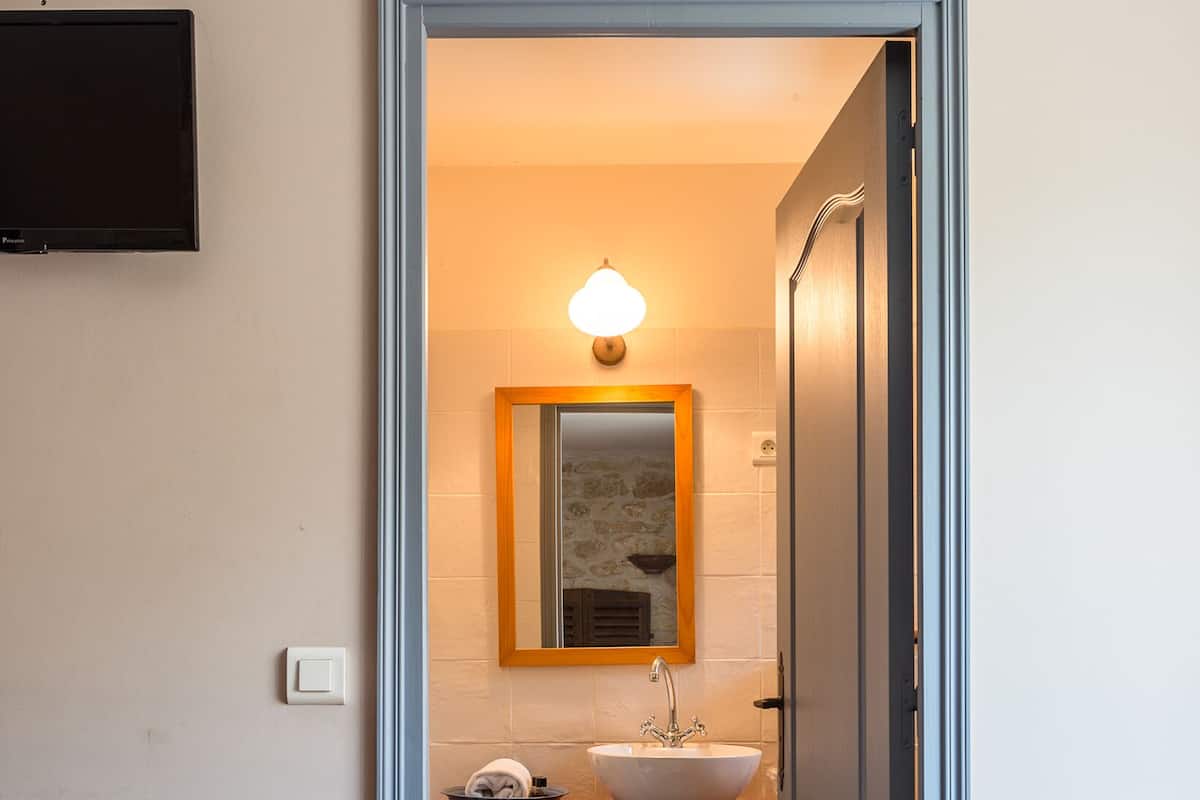A bathroom with a sink, mirror, and light fixture.