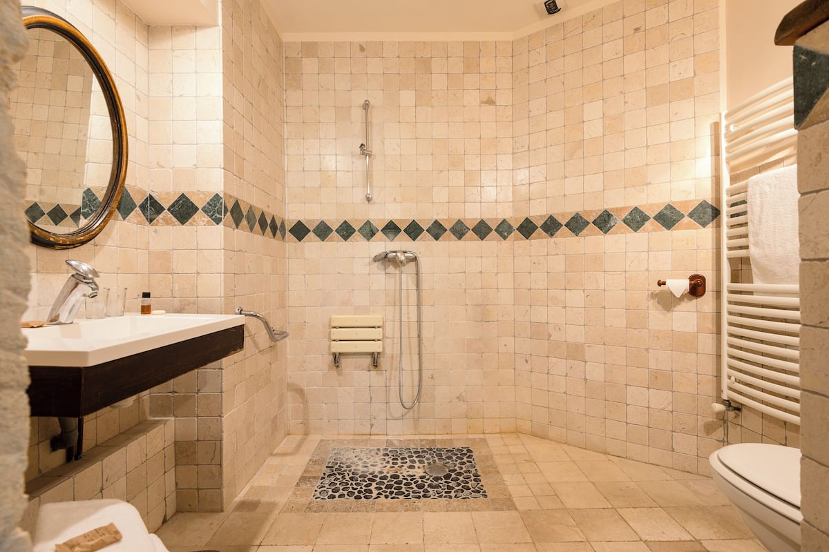 A bathroom with a sink, mirror, shower, and toilet.