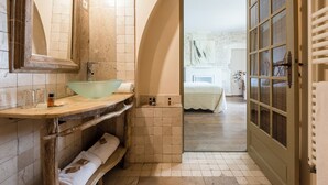 Un baño con un espejo grande, un lavabo, un perchero para toallas y una puerta que da a un dormitorio.