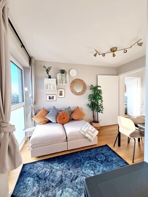 Un dormitorio moderno con cama, mesitas de noche, cómoda y un ventanal con vistas a la ciudad.