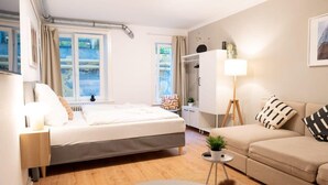 Ein modernes Hotelzimmer mit Bett, Sofa, kleinem Tisch, Lampe und Kleiderschrank.